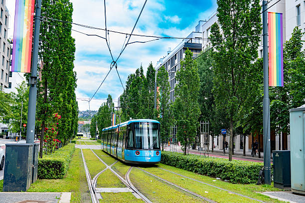 Oslo, Blue tram on Dronning Eufemias gate in Norway, showing modern buildings, trees and urban summer atmosphere.