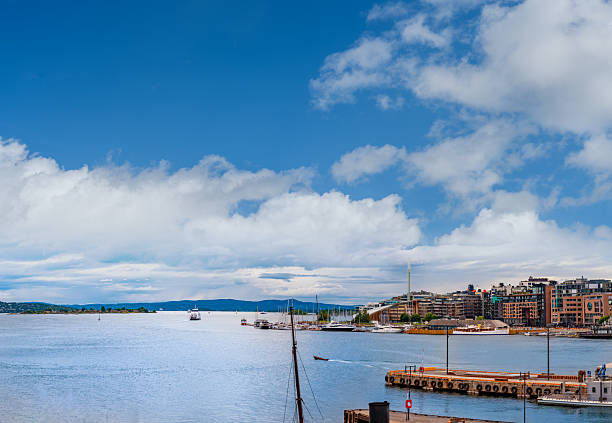 Harbor view of Pipervika bay in Oslo Norway, showing Aker Brygge style waterfront buildings, boats and blue summer sky