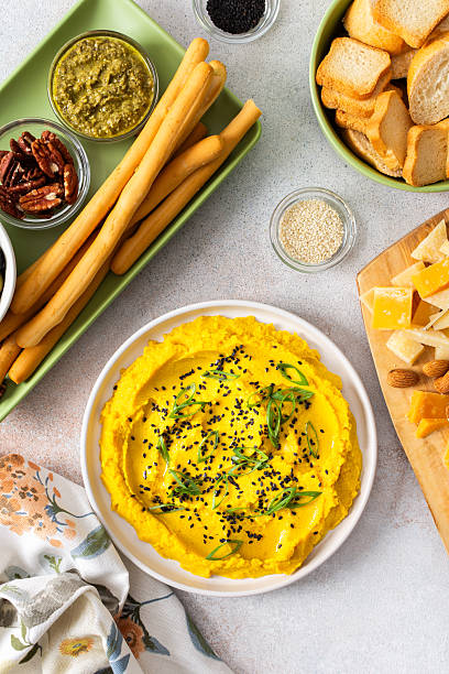 Gather around a colorful charcuterie board featuring turmeric hummus, cheese, nuts, and olives. This delightful spread invites friends to share tasty bites and enjoy each other company