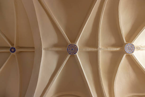 Vaulted ceiling ribs supporting decorative keystones showing geometric patterns inside an old building