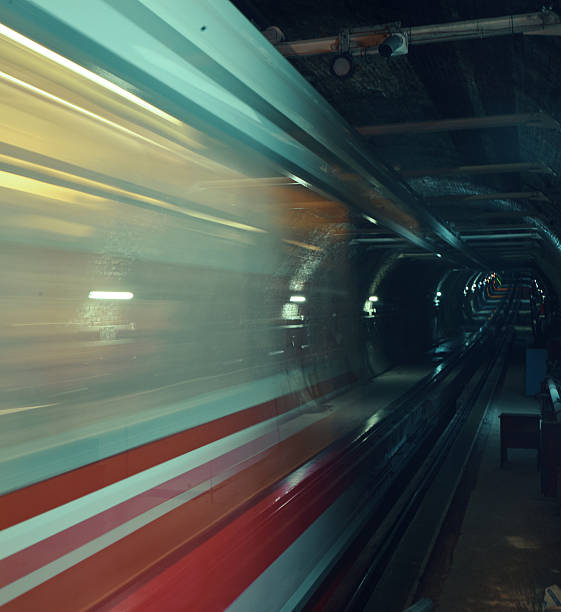 Subway train moving fast on its tracks inside a dark underground tunnel, creating motion blur and speed effect