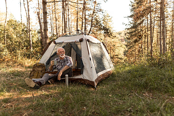 istock Senior man enjoying morning coffee while camping in forest 2256911892