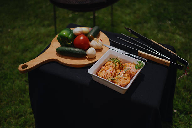Marinated chicken pieces and assorted fresh vegetables on a cutting board, ready for a backyard barbecue grilling session