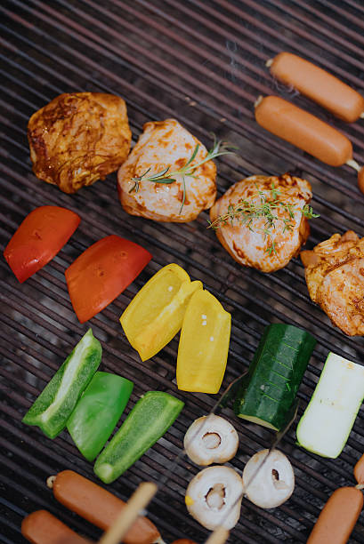 Grilling chicken, sausages, and vegetables on a barbecue
