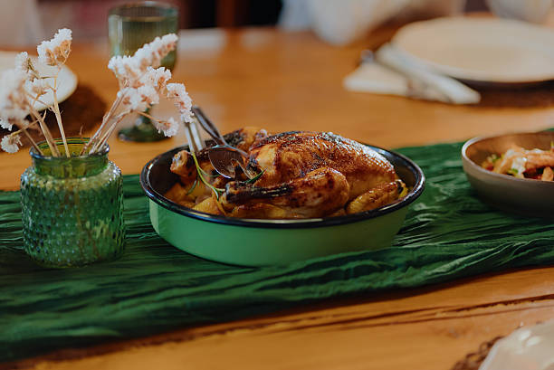 Whole roasted chicken and potatoes in a skillet, ready for serving during a family dinner on a wooden table