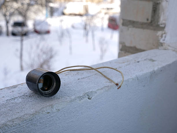 Old electric socket with wires on concrete balcony railing in winter outdoors.