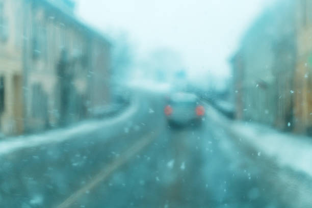 Blurred view of driving in heavy snowfall through car windshield, selective focus.