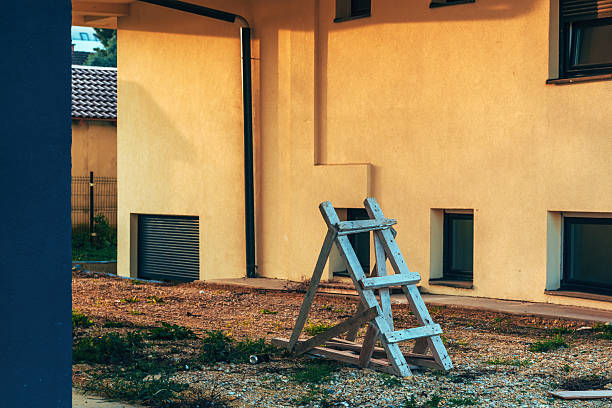 A primitive wooden staircase leading to the sky on the roof of a modern brown brick building. Background.