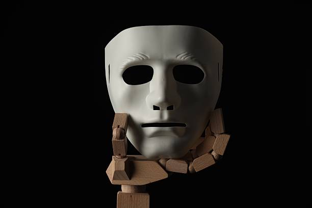 Wooden mannequin hand holding plastic mask on black background. Theatrical performance