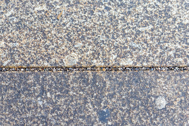 Gray stone slab surface showing rough texture and a seam filled with small gravel