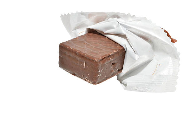 A candy with a wafer filling covered in chocolate with the packaging not completely removed.