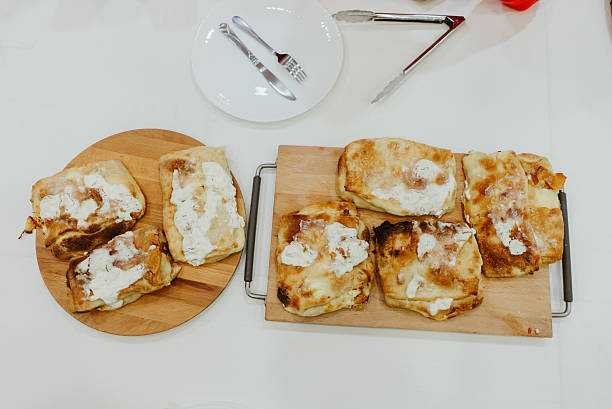 Freshly baked burek, a traditional savory phyllo pastry filled with cheese, cooling on wooden cutting boards