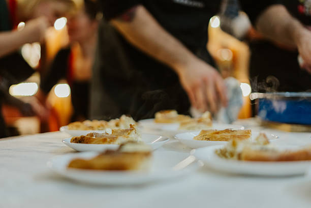 Chef plating steaming gourmet dishes on small white plates, hands arranging food in a busy restaurant kitchen, close-up expertise
