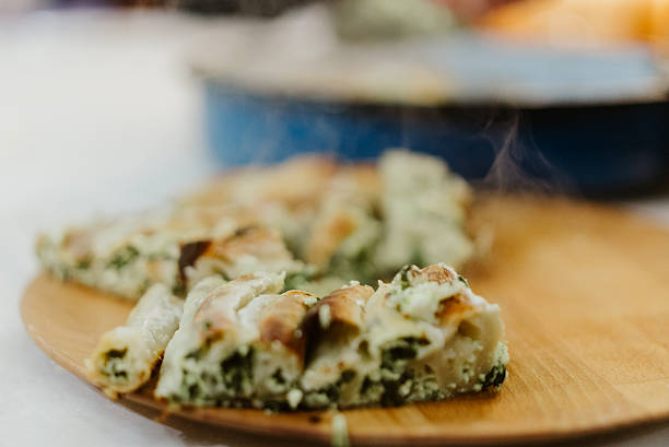 Steaming hot spinach and cheese burek, a traditional Balkan pie, served on a rustic wooden board, a savory homemade comfort food