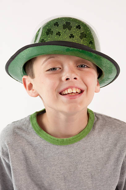 Smiling boy looking at camera wearing festive  St. Patrick's Day hat with shamrocks.