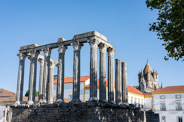 Roman Temple in Evora Portugal with a blue sky and roofs in the background.