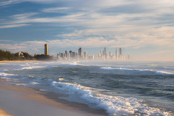 Golden morning light and waves coming into shore on at Burleigh Heads Beach, Gold Coast, Queensland with the cityscape skyline of Surfers Paradise.