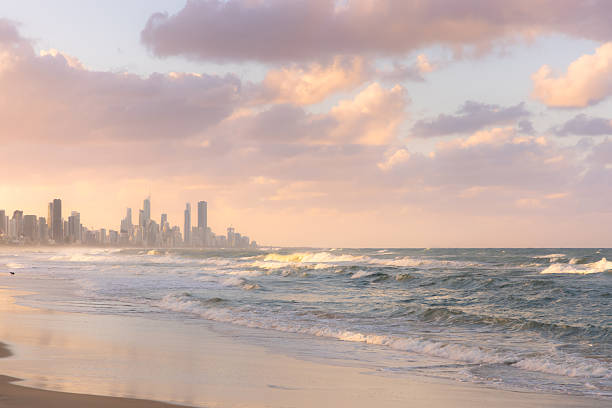 Serene, peaceful sunset along Burleigh Beach in with view of Surfers Paradise cityscape skyline from Burleigh Heads, Gold Coast, Queensland, Australia.