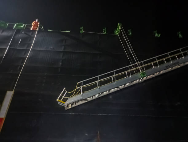 istock Night boarding of a cargo ship with lowered gangway ladder. 2256944018