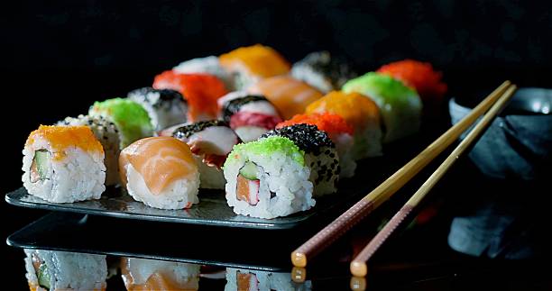 Vibrant Sushi Rolls On Slate Plate Showcasing Assorted Salmon And Tuna Maki With Avocado, Sesame, And Sticky