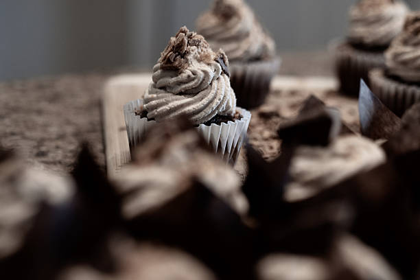 Close‑up of a chocolate cupcake topped with vanilla buttercream icing and pieces of chocolate‑covered toffee.