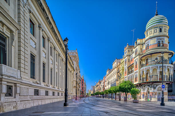 View of Constitution Avenue in Seville, Spain. The dome of the Adriatica Building is visible in the foreground. Long exposure blurs pedestrians.