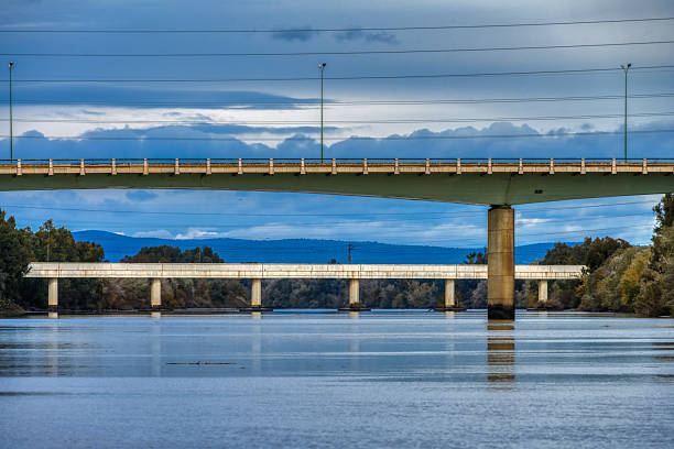 View of the SE30 bridge and the railway bridge behind it over the Guadalquivir River near Cartuja Island in Seville, Andalusia, Spain.