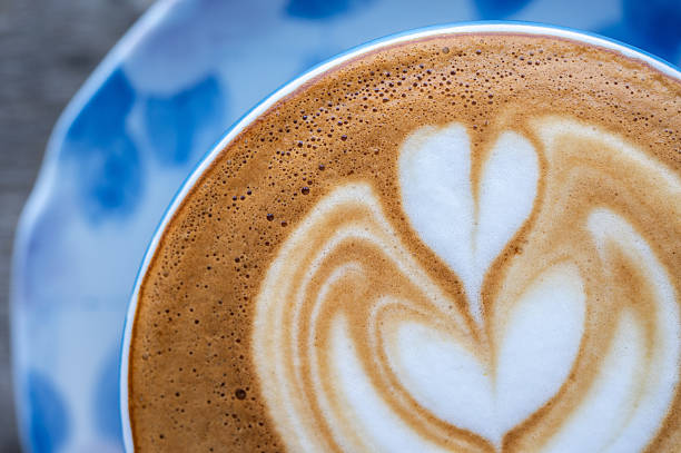 Cropped shot view of the heart on surface of hot latte coffee.