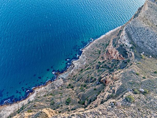 Topdown rocky coastline turquoise shallows clear water visible strata geologist drone survey documenting