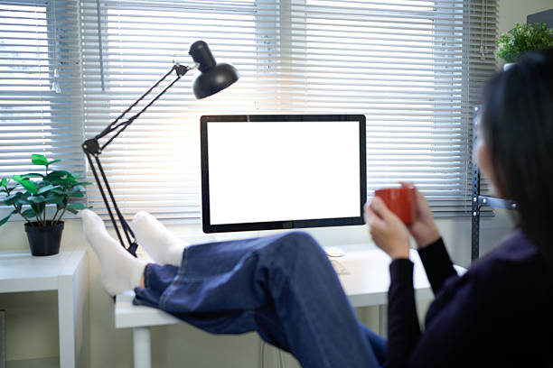 woman relaxing with coffee and computer white screen in modern office workspace.