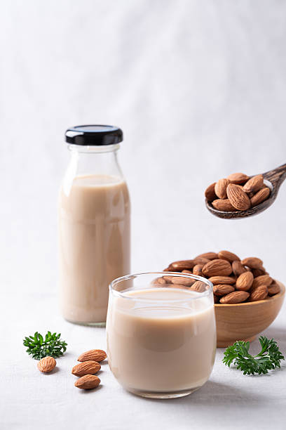 Almond milk and almond nuts on white fabric background