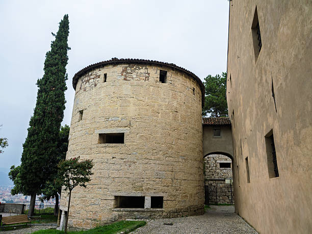 Brescia, Italy - october 12 2025: Round Stone Tower Next To Building Wall And Tall Cypress Tree , Brescia, Italy.