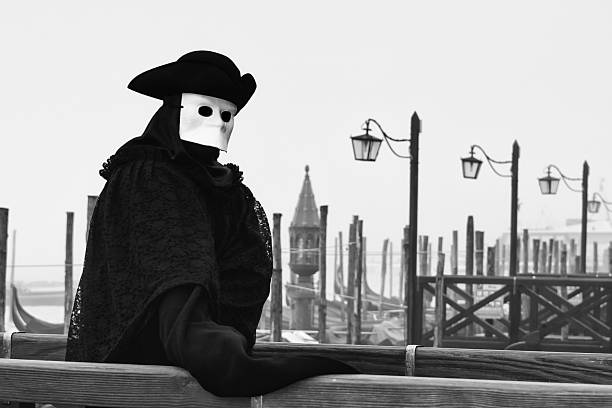 Carnival of Venice. Beautiful and mysterious traditional venetian mask 'Bauta' with gondolas wrapped in morning mist