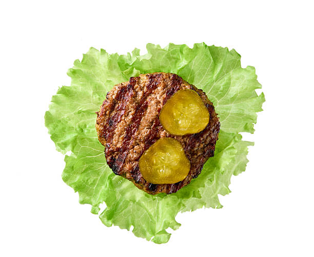 grilled hamburger beef patty with  fresh lettuce leaves isolated on white background, top view.