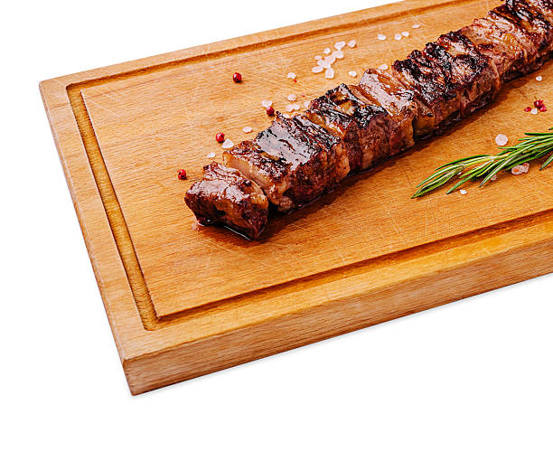 Perfectly grilled meat on a wooden board with herbs and seasoning