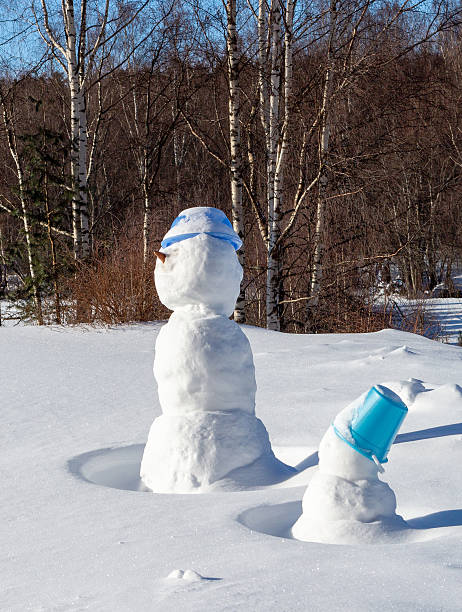 Snowmen stuck in a snowdrift. Sunny winter day after a blizzard.
