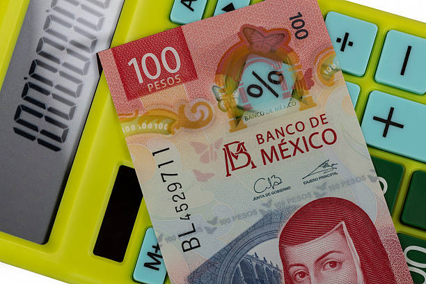A 100 Mexican peso bill with a calculator in the background