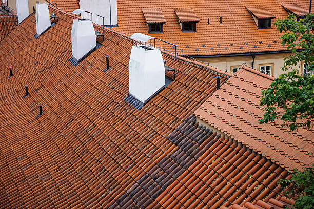 An aerial view of traditional orange clay tile rooftops with prominent chimneys and a vibrant architectural design, capturing the essence of European urban aesthetics.