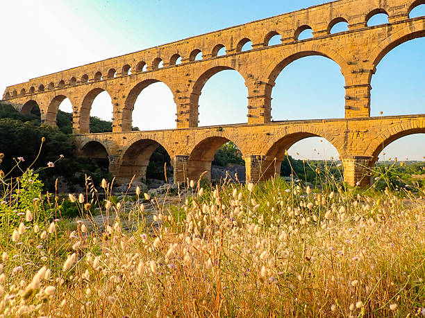 Pont du Gard is an ancient Roman aqueduct bridge over the river Gardon in the French Gard department during a summer sunset