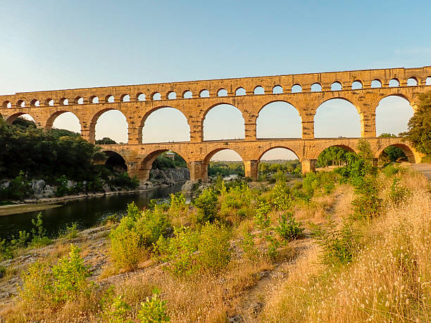 Pont du Gard is an ancient Roman aqueduct bridge over the river Gardon in the French Gard department during a summer sunset