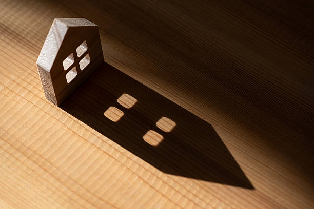 A symbolic wooden house with a long shadow