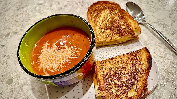 Tomato bisque soup with deluxe grilled cheese sandwich on a plate.