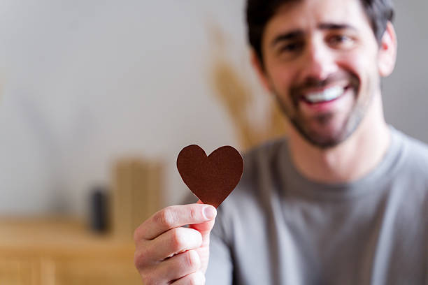 Smiling man holding a handmade heart symbolizing love and connection