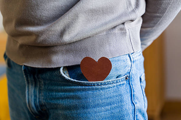 Person carrying a brown heart in a blue jeans pocket