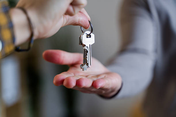 Person's hand passing house keys to another person's open palm