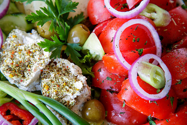 Mixed vegetable salad and cheese on a plate served on restaurant table, full frame, close-up