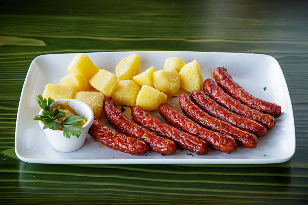 Grilled red sausages served with baked potato and mustard dip in rectangular plate