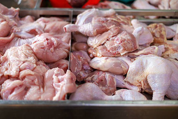 Raw chicken parts displayed in a stainless steel tray at a fresh market stall. The close-up view highlights uncooked poultry meat prepared for sale, representing food supply, grocery shopping, and fresh ingredients commonly used in home cooking and food preparation.