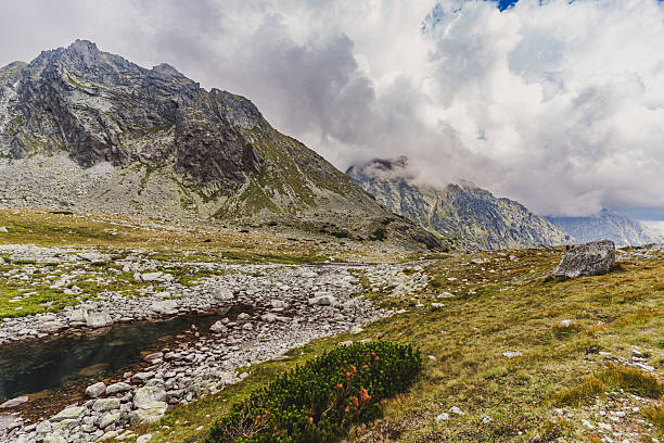 High mountain lake Velké Hincovo pleso surrounded by rocky peaks and dramatic clouds in the High Tatras, Slovakia. Remote alpine landscape and wilderness nature scenery.