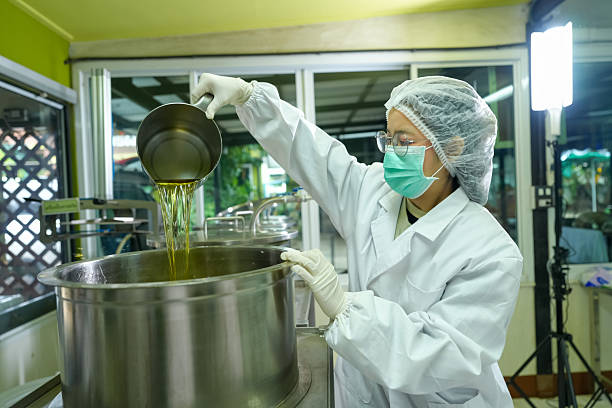 A worker carefully pours oil into a large pot in a culinary workshop showcasing food safety and quality in oil production.